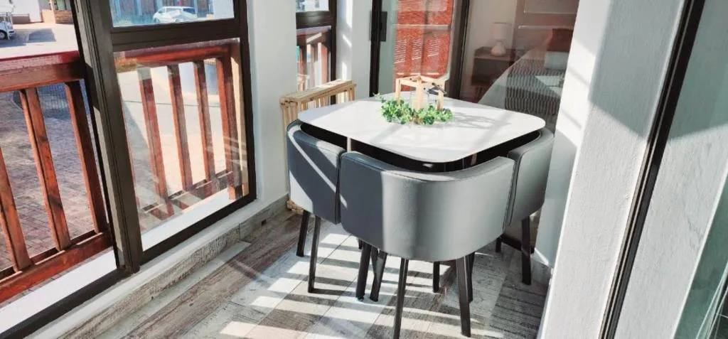 Modern dining table with chairs by windows in bright apartment space