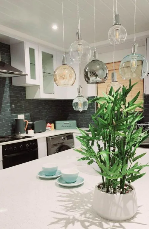 Modern kitchen with black tile backsplash, white cabinetry, pendant lights