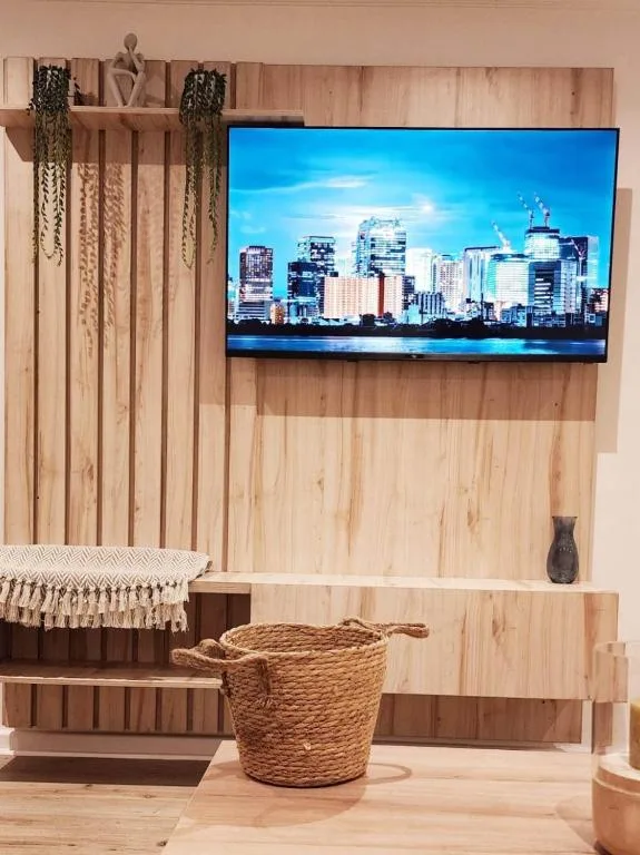 Modern lounge with mounted TV, wooden accent wall, and woven storage basket