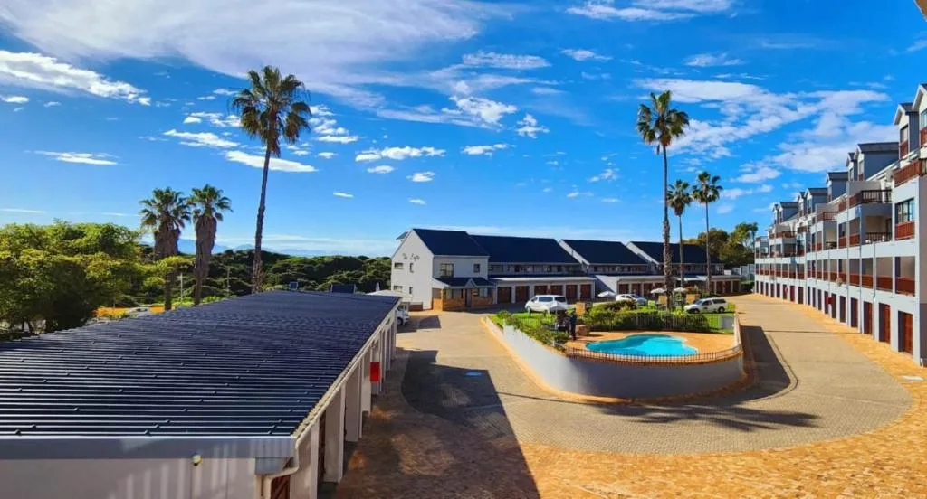 Resort courtyard with swimming pool, palm trees, and apartment buildings