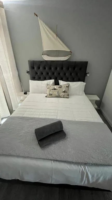 Modern bedroom with black upholstered headboard and nautical sailboat decor