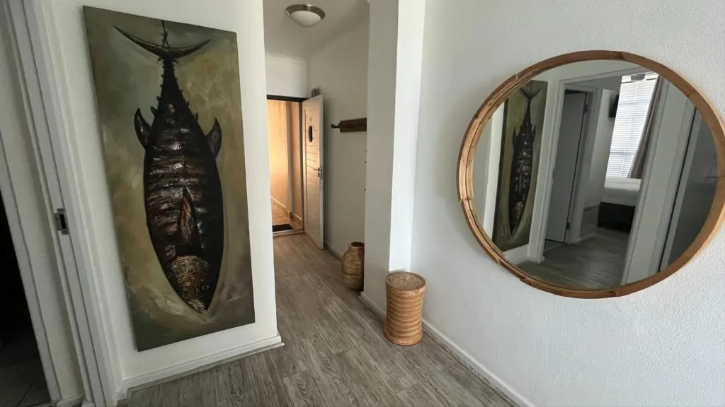 Hallway with fish artwork, round mirror, and decorative coastal-themed furnishings