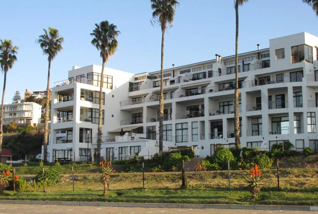 White apartment building with palm trees and manicured garden landscape