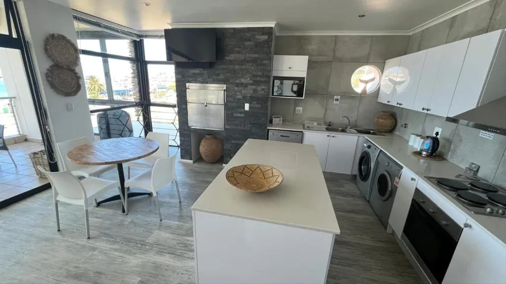 Modern open-plan kitchen with island, stainless steel appliances, and dining area