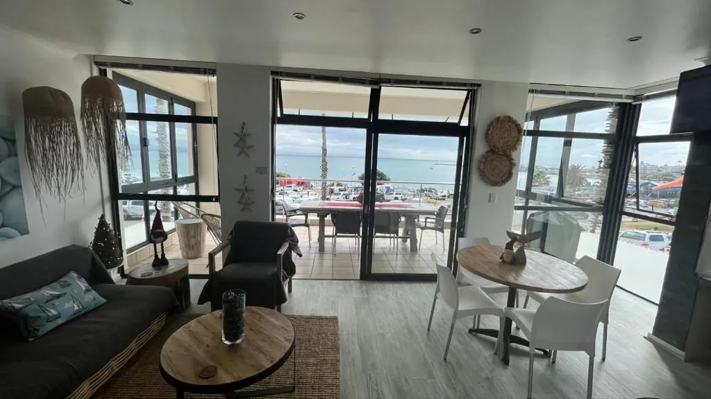 Modern open-plan lounge with ocean views through large windows and glass doors