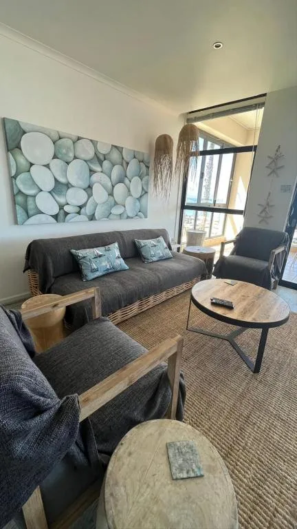 Bright lounge with gray sofa, wooden furniture, and coastal artwork