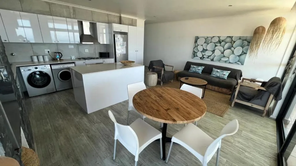 Open-plan living area with dining table, sofa, and kitchen visible