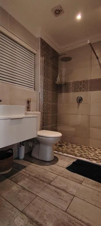 Modern bathroom with shower cubicle, white vanity, and tiled flooring