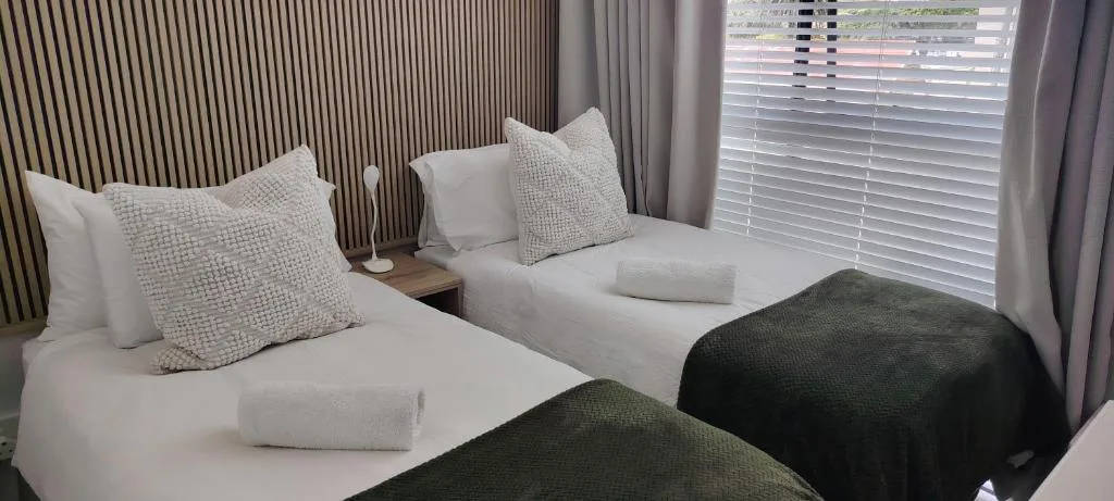 Twin beds with white linens and textured pillows in bright room
