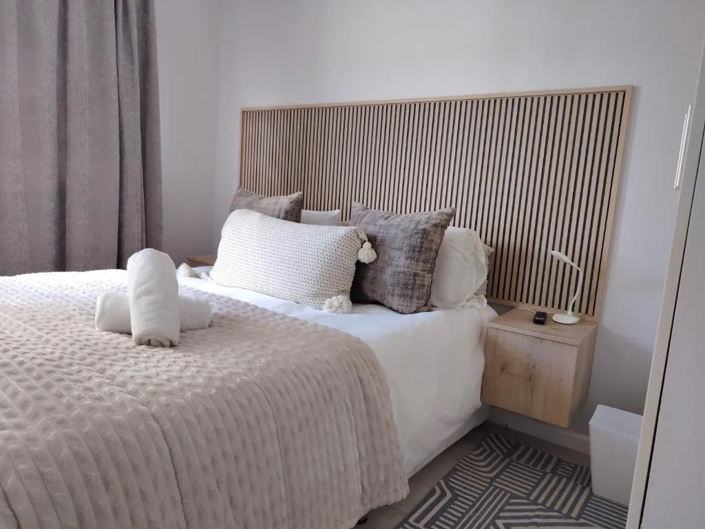 Modern bedroom with striped headboard, white bedding, and neutral décor
