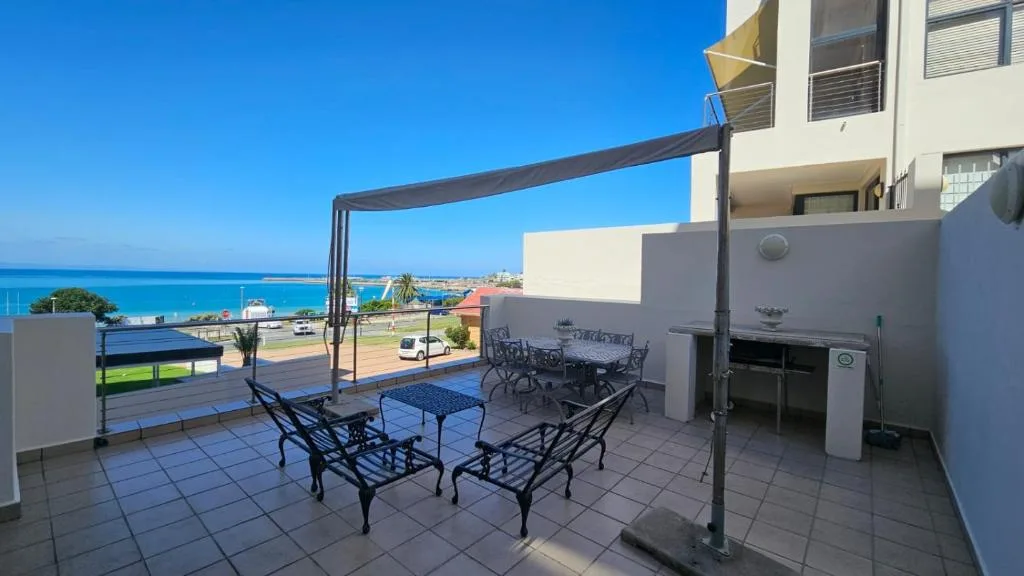 Oceanview terrace with seating, shade sail, and built-in braai area