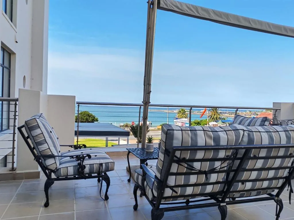 Shaded patio with striped loungers overlooking sea and coastal town