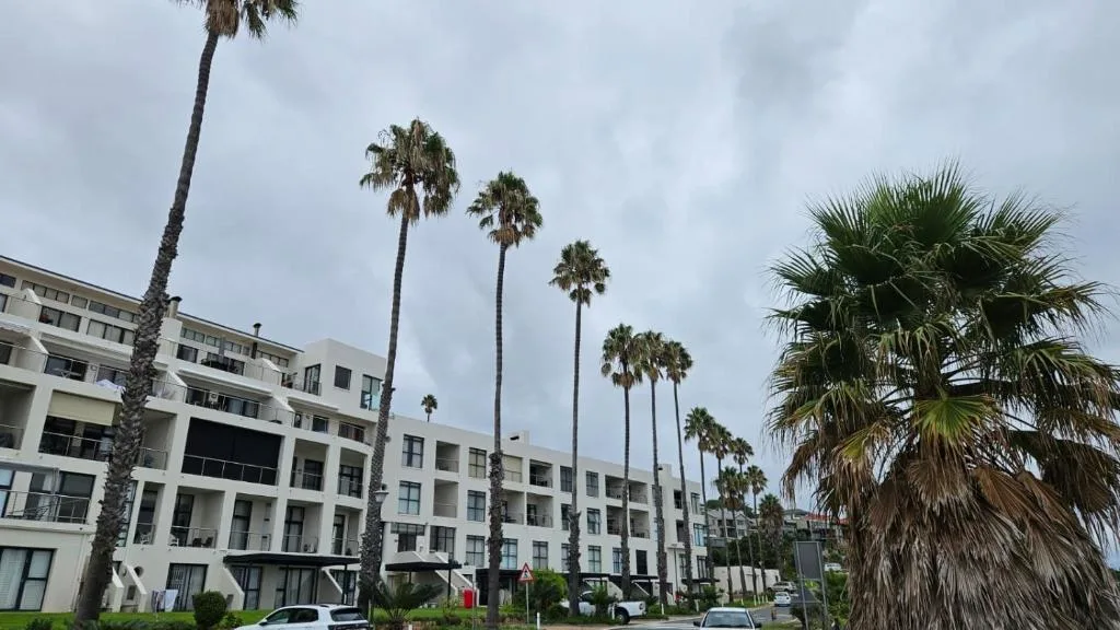 Modern white apartment building with palm trees and manicured gardens