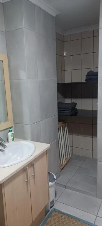 Modern bathroom with vanity sink, large tiled shower enclosure, and gray tile flooring