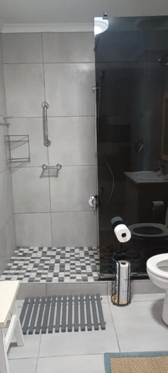 Modern bathroom with enclosed shower, toilet, and checkered floor tiles