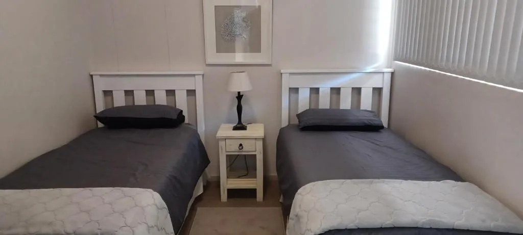 Twin bedroom with white headboards and dark bedding, shared nightstand between beds