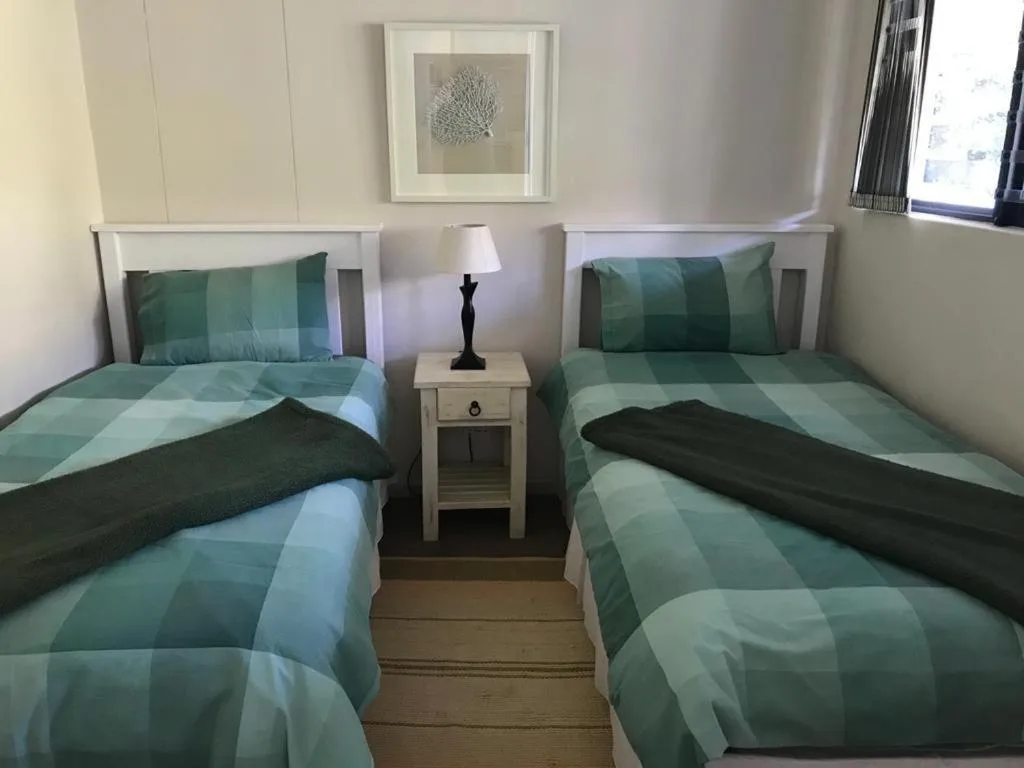 Twin bedroom with green checkered bedding and shared nightstand lamp