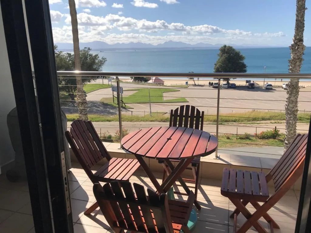 Oceanfront deck with wooden chairs and table overlooking bay