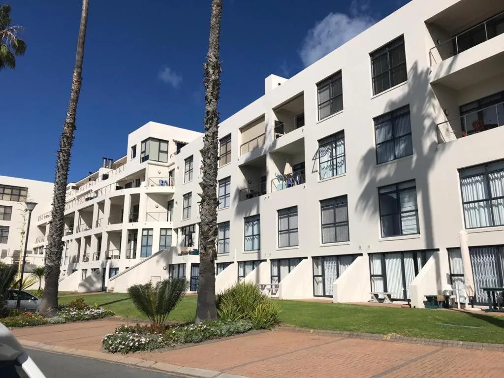 Modern white apartment building with palm trees and manicured garden