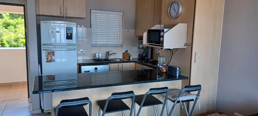 Modern kitchen with white refrigerator, black countertop, and bar seating