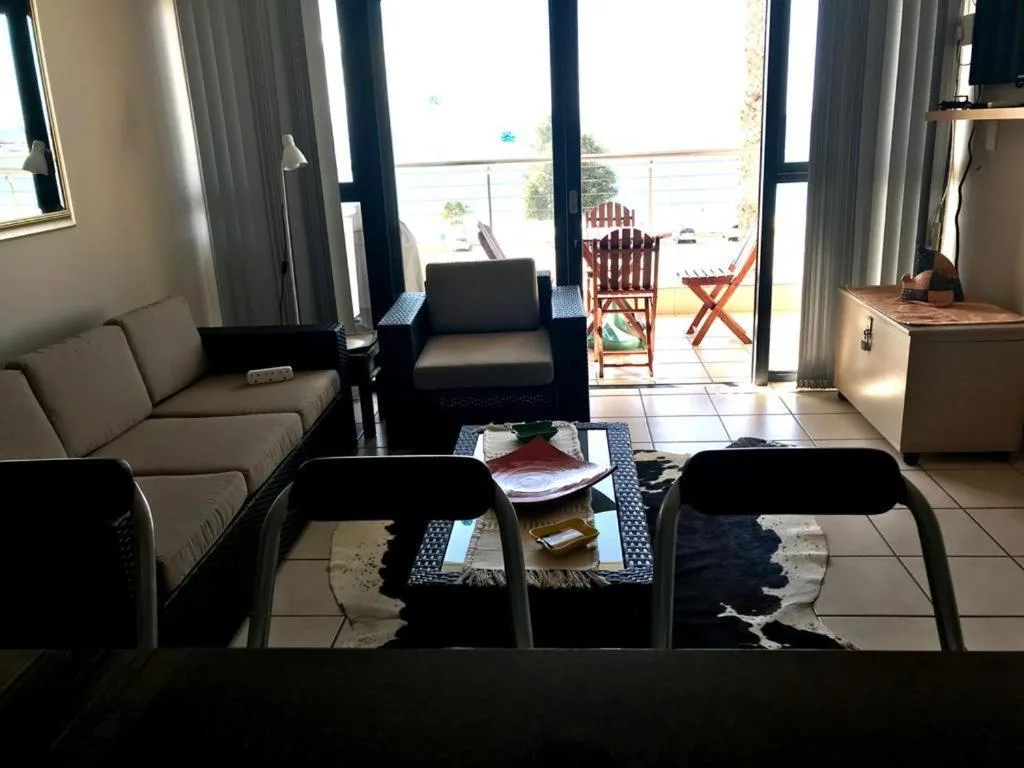 Bright lounge with sofa, armchair, and ocean views through sliding doors