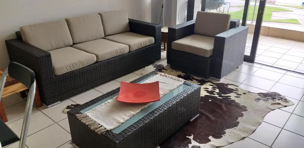 Modern lounge with black wicker furniture and beige cushions overlooking garden