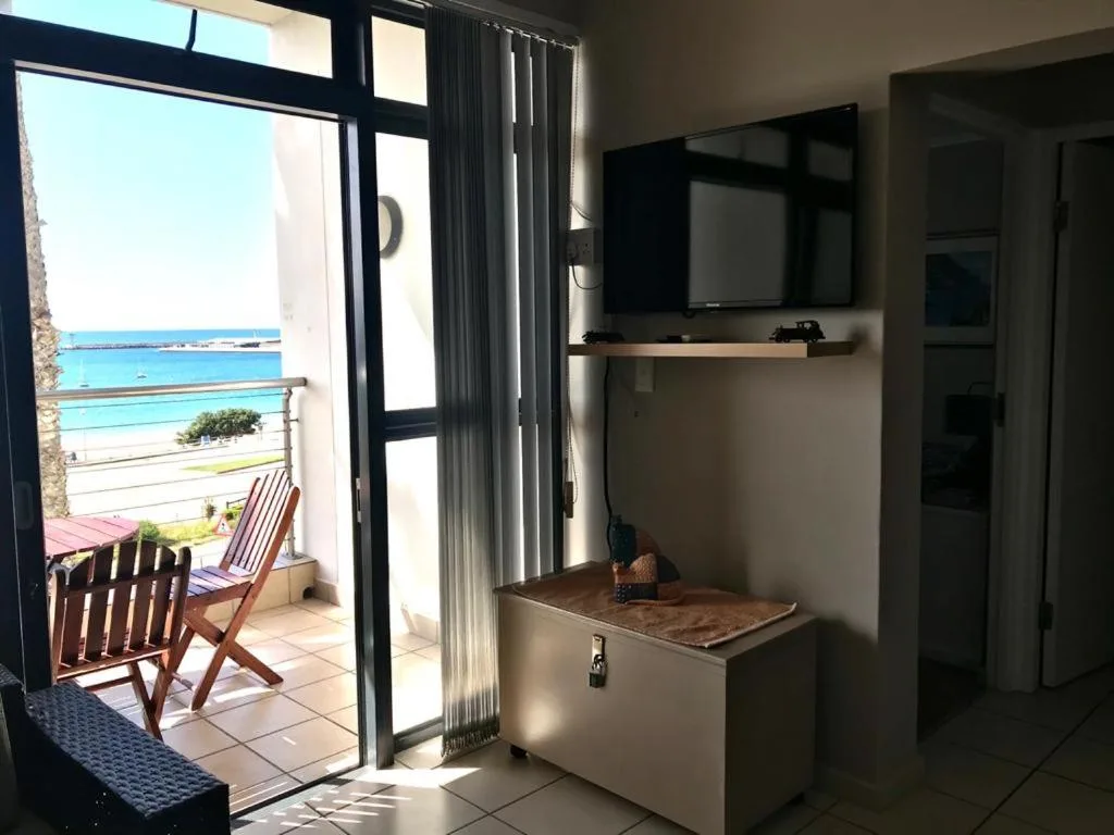 Bright lounge with wall-mounted TV and ocean views through glass doors