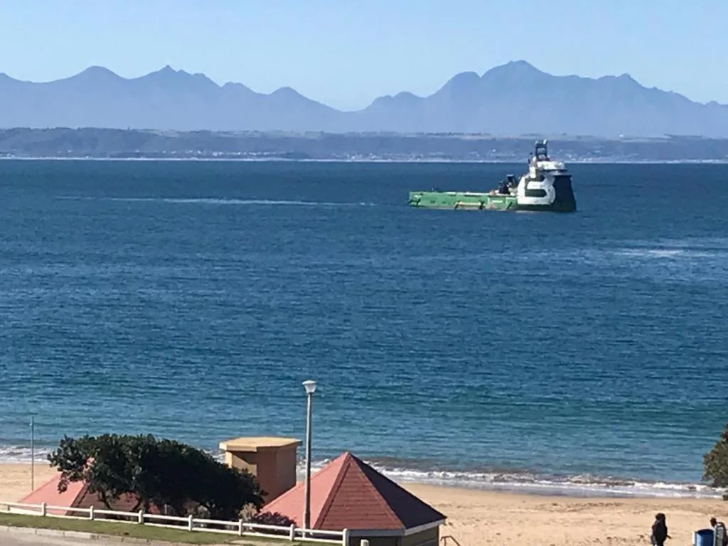 Ocean view with mountains, beach, and industrial vessel offshore