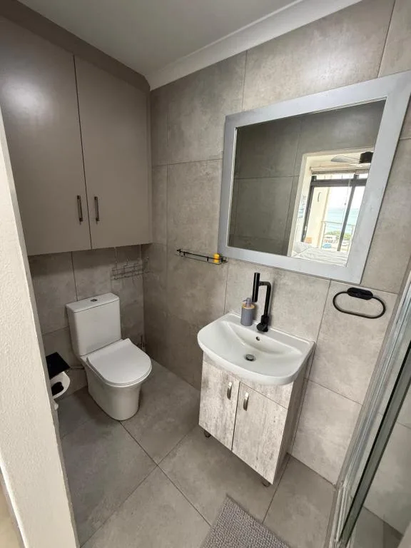 Modern bathroom with toilet, vanity sink, and framed mirror above