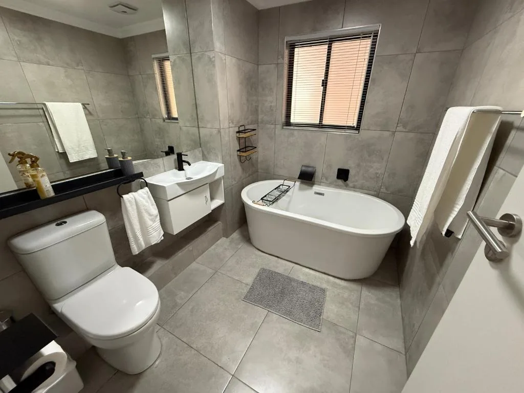 Modern bathroom with freestanding bathtub, vanity, toilet, and tiled floors