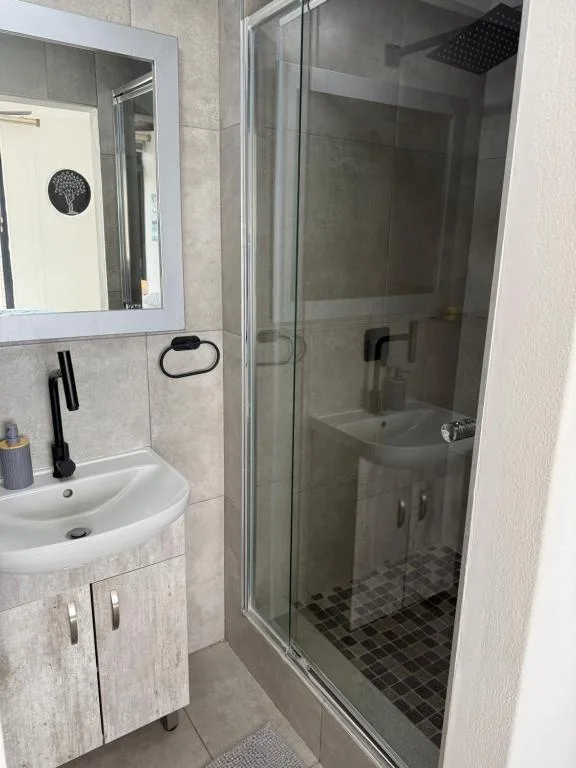 Modern bathroom with vanity sink, mirror, and enclosed shower cubicle