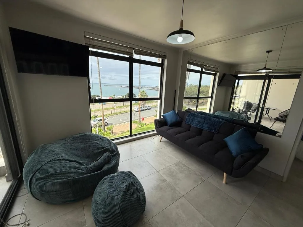 Modern lounge with black sofa, bean bags, and panoramic sea views through large windows
