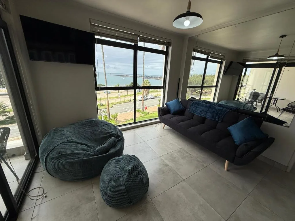 Modern lounge with black sofa and bean bags overlooking coastal views