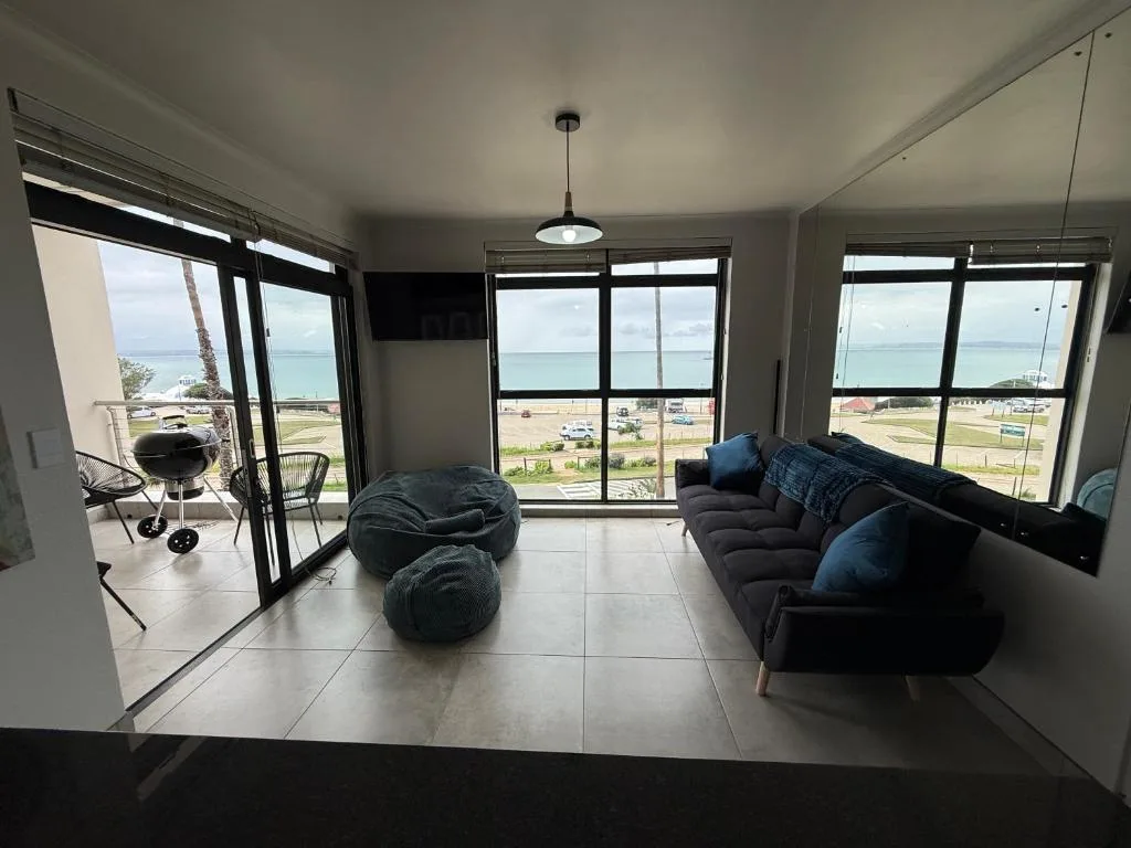 Spacious lounge with black sofa, bean bags, ocean and beach views through large windows