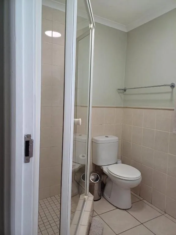 Clean bathroom with shower enclosure, toilet, and tiled walls