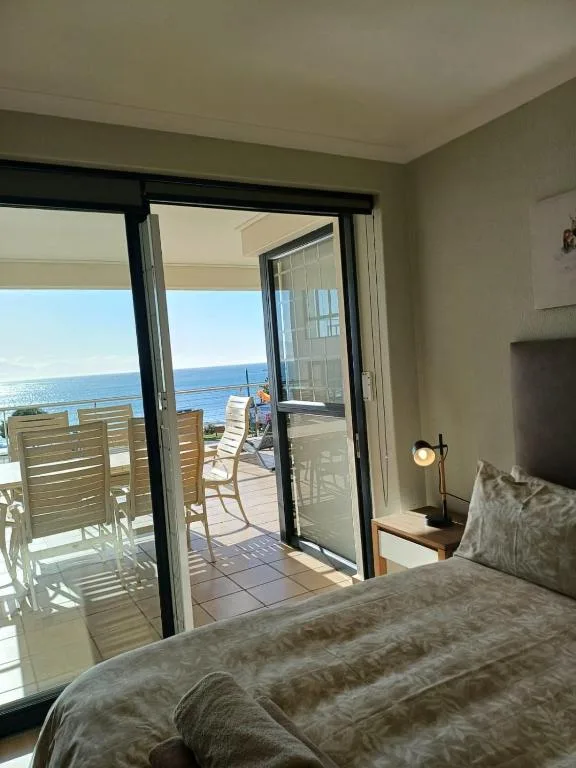Bedroom with sea view through open patio doors to deck