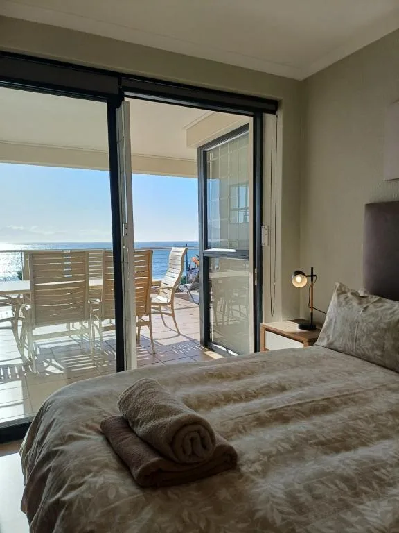 Bedroom with ocean views through sliding glass doors to deck