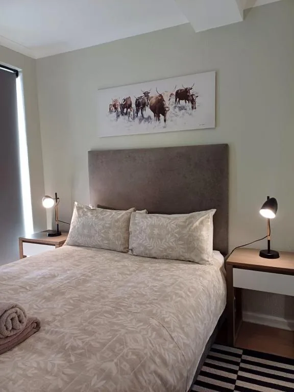 Bright bedroom with gray upholstered headboard and patterned bedding