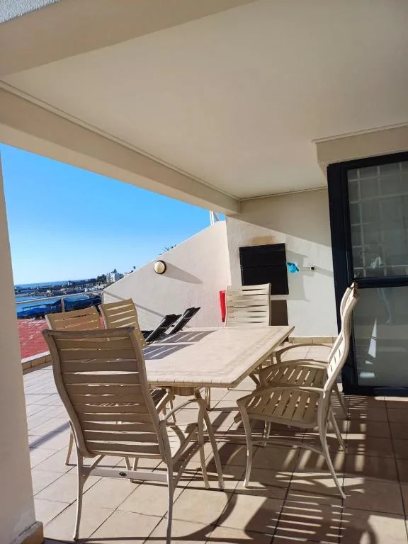 Covered patio with dining furniture and ocean view beyond