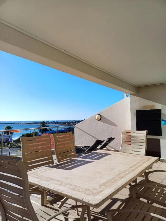 Waterfront deck with dining table, lounge chairs, and lagoon views
