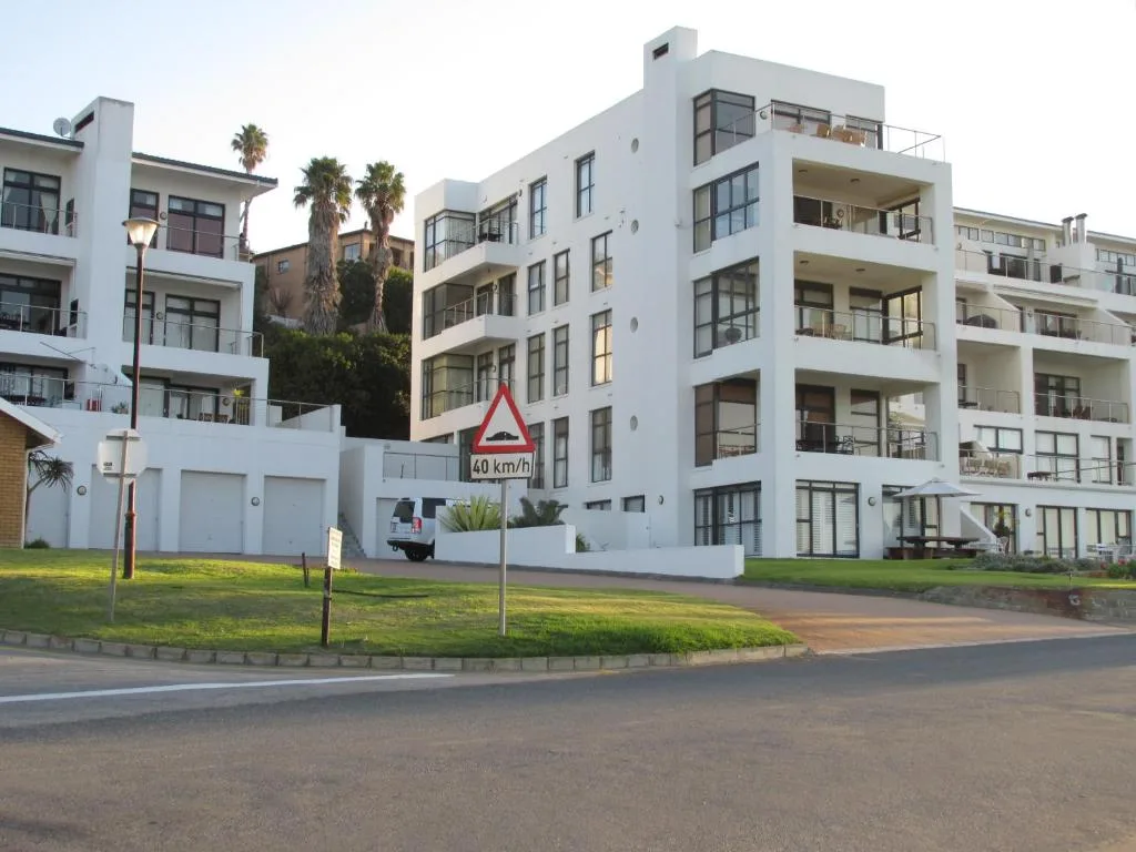 Modern white apartment building with multiple balconies and palm trees