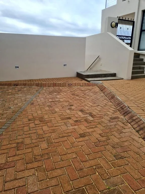 Modern white building exterior with brick paved courtyard and unit number signage