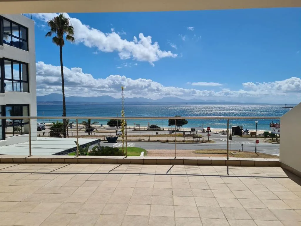 Expansive ocean and mountain vista from beachfront deck with palms