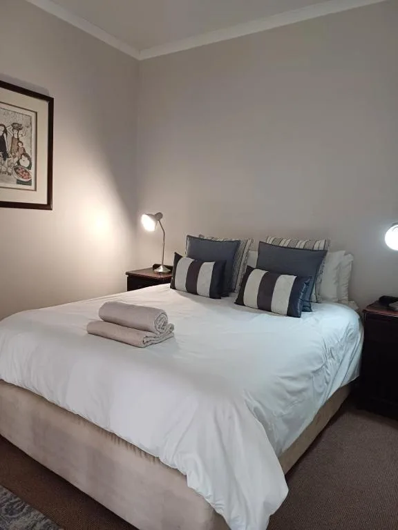Clean bedroom with white bedding, striped pillows, and side table lamp