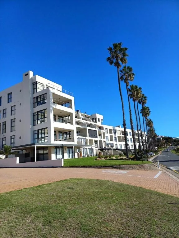Modern white apartment building with palm trees and manicured gardens