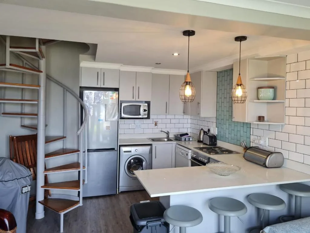 Modern kitchen with white cabinetry, stainless steel appliances, and pendant lighting