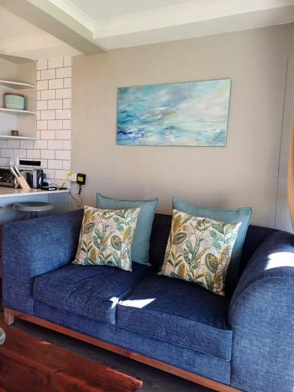 Comfortable blue sofa with patterned cushions and ocean-themed wall art