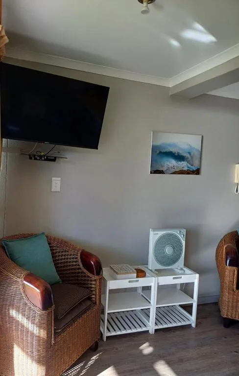 Living room with wicker chair, wall-mounted TV, and coastal artwork
