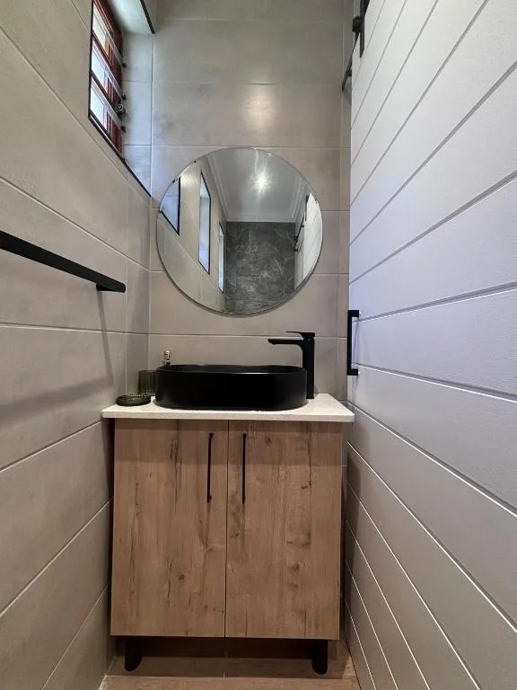 Modern bathroom vanity with black vessel sink and round mirror