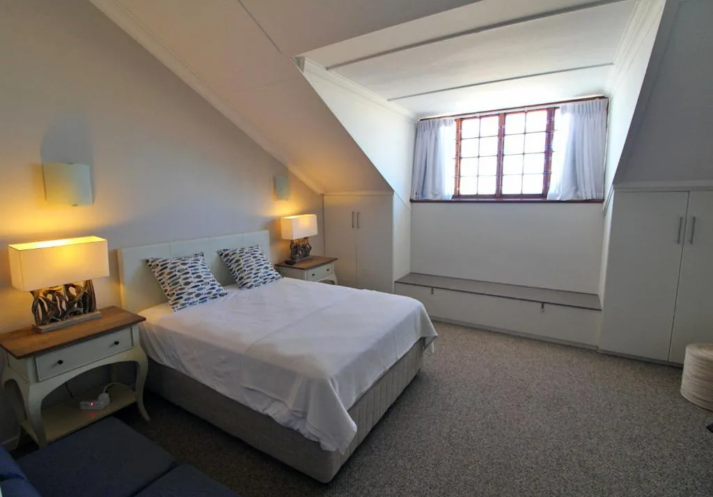 Bright attic bedroom with double bed, bedside lamps, and skylight window